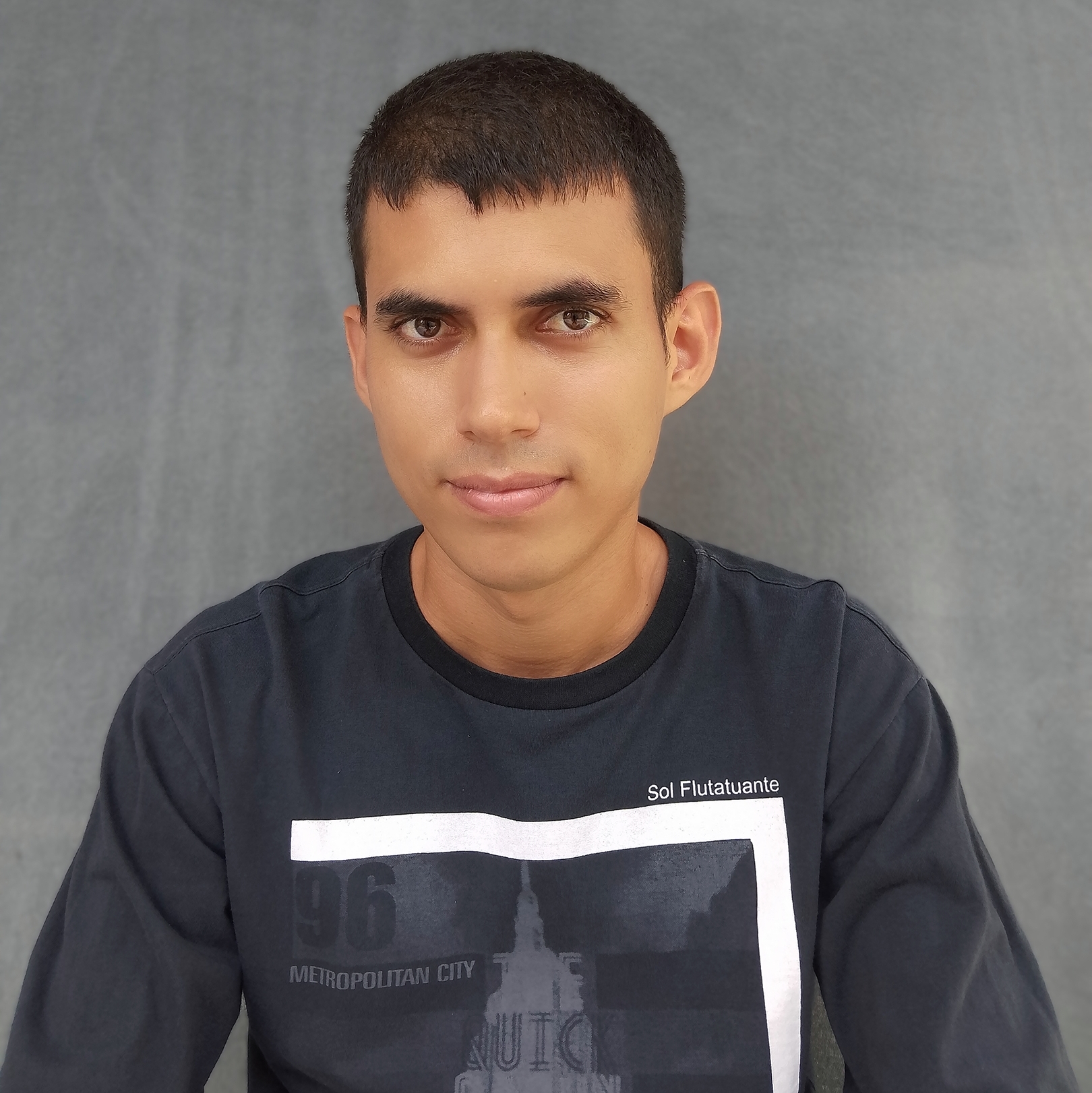 A picture of me with a more serious expression, same background and shirt as the previous picture.